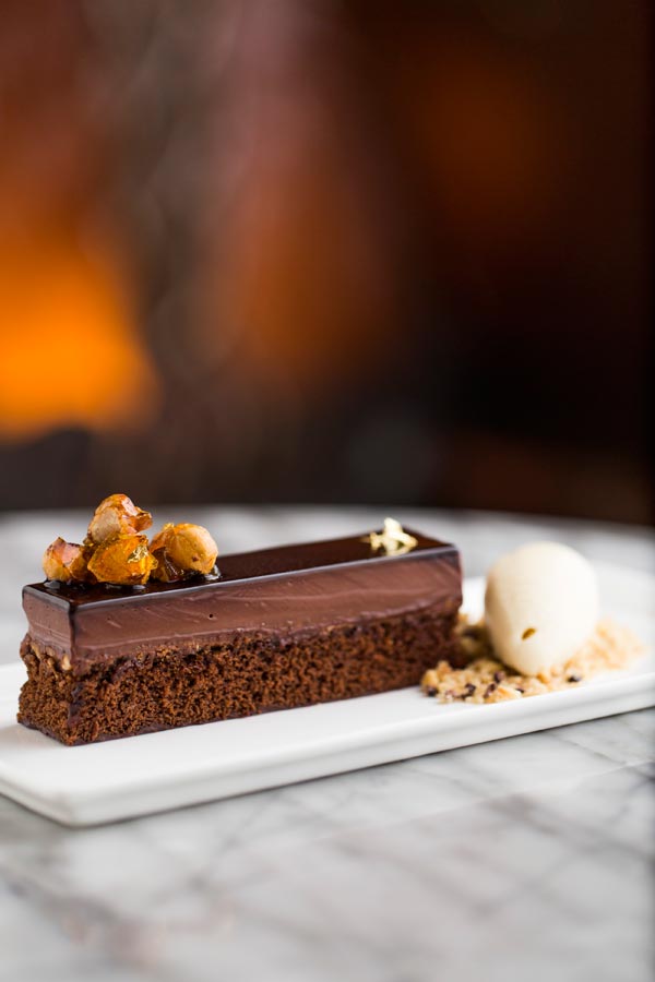 A chocolate dessert plated with gold-flecked spheres
