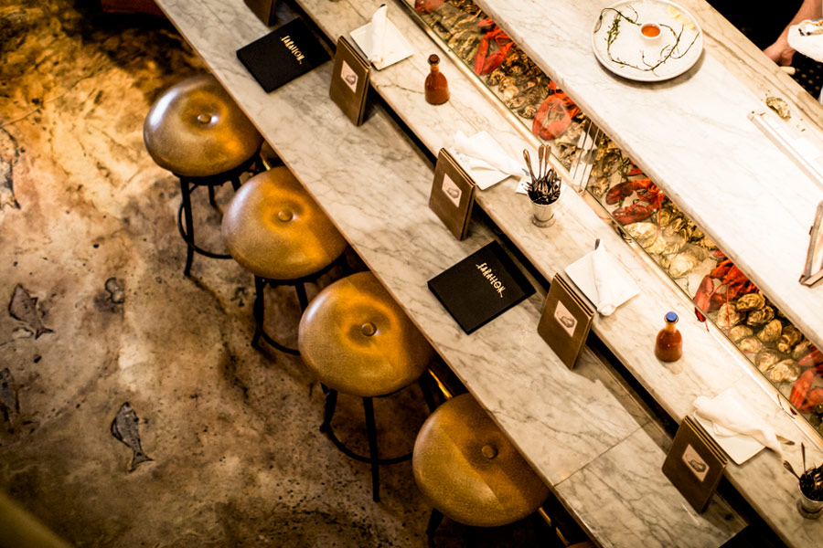 Guests seated along the marble raw bar